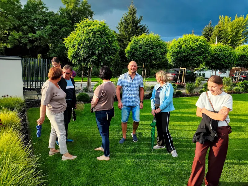 Klubowicze rozmawiają w ogrodzie podczas spotkania